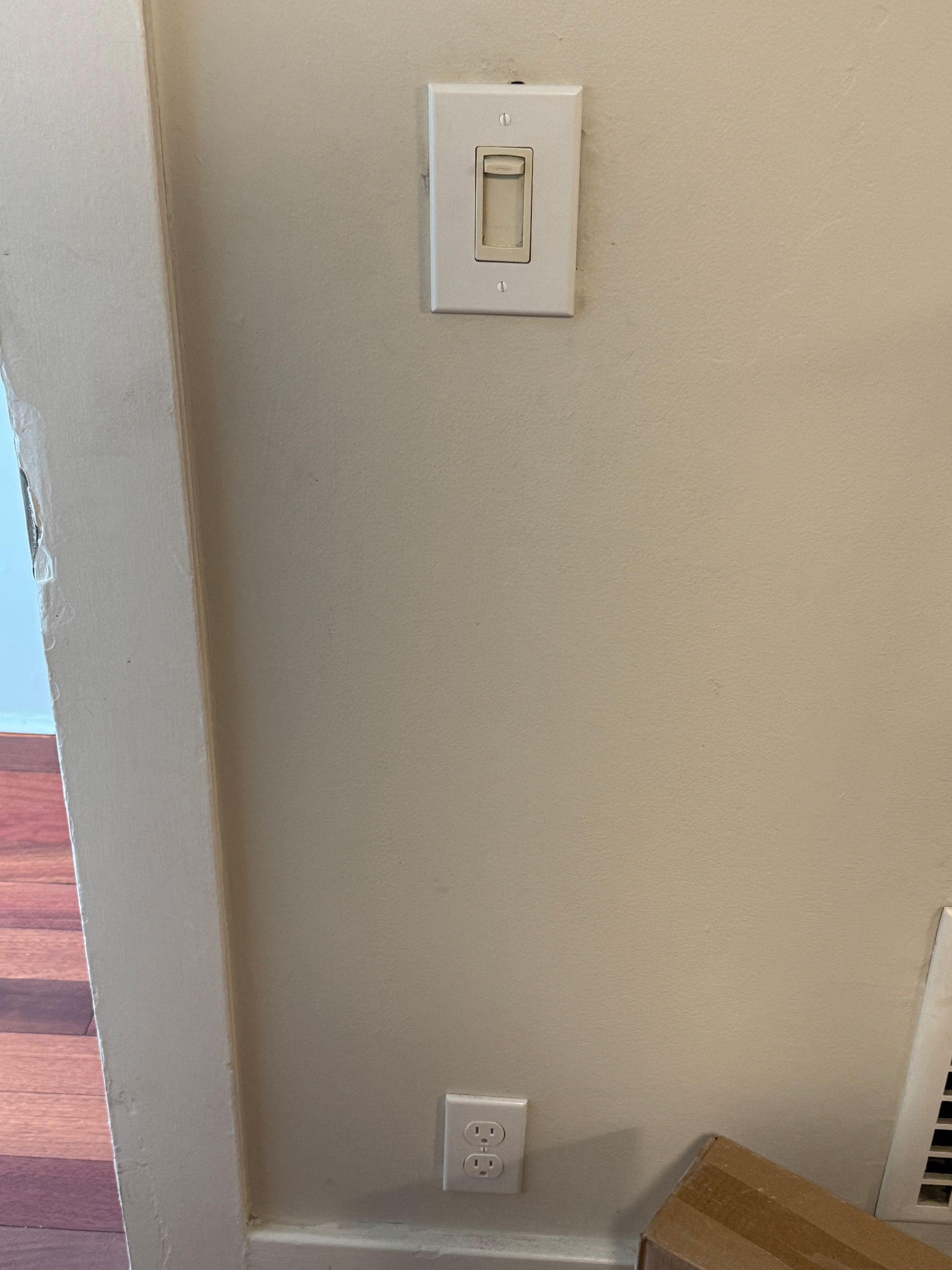White switch plate and outlet on a beige wall, with an empty switch opening.