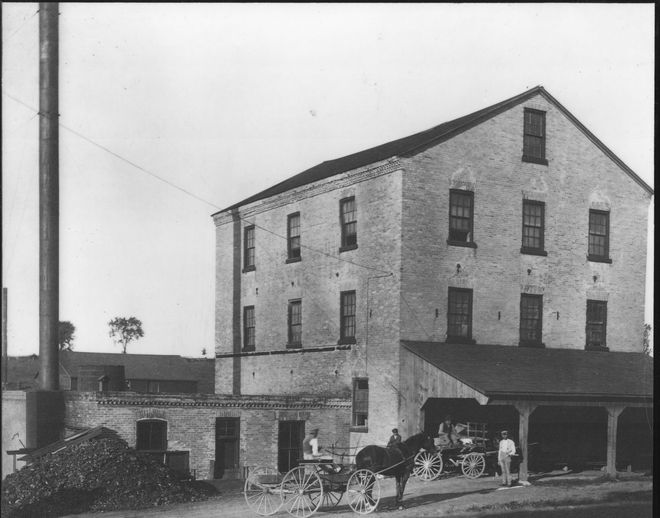 A horse drawn carriage is parked in front of a large brick building