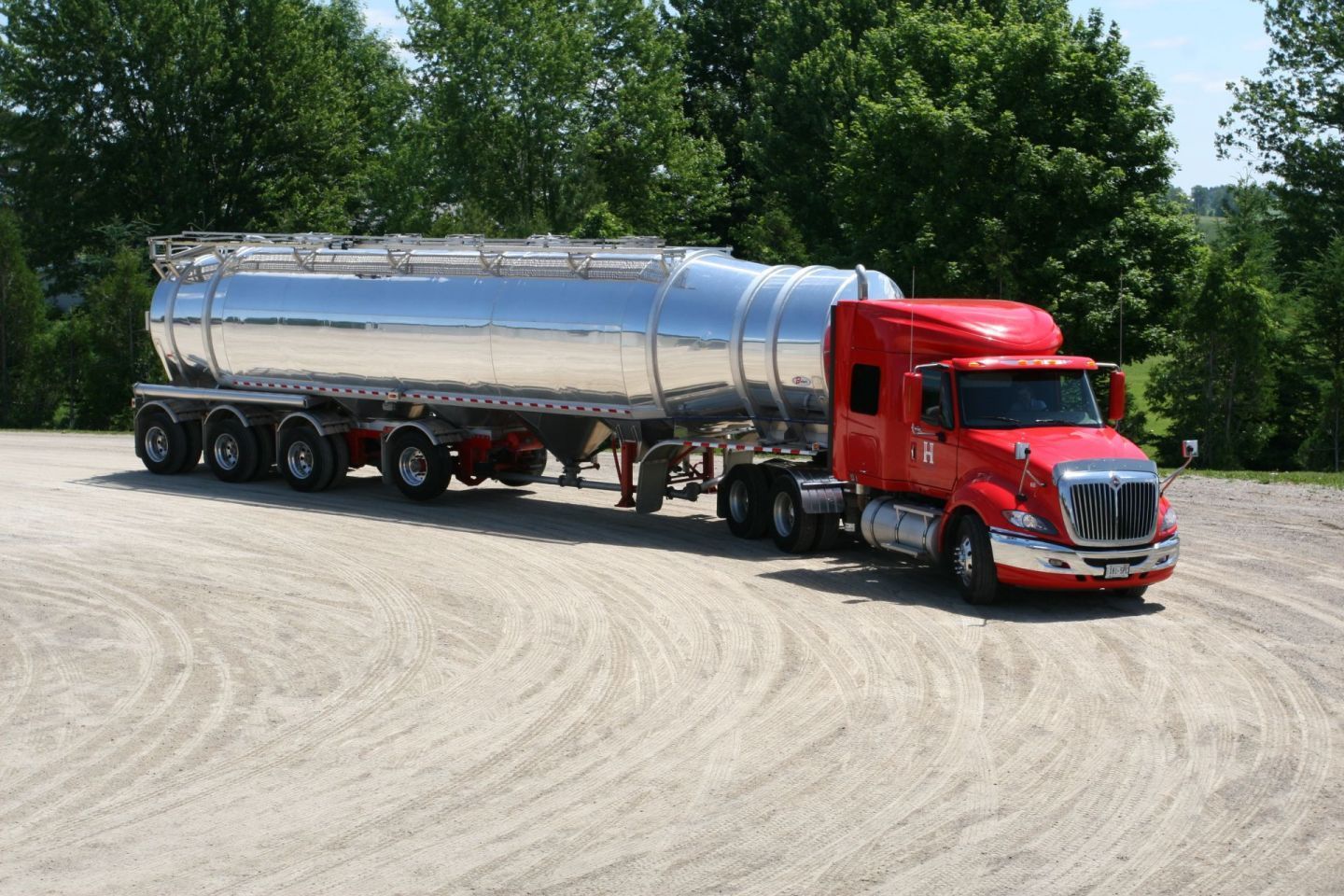 A red and silver semi truck is parked on a dirt road