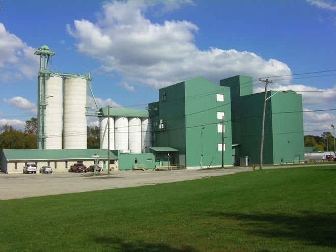 A large green building with silos in front of it