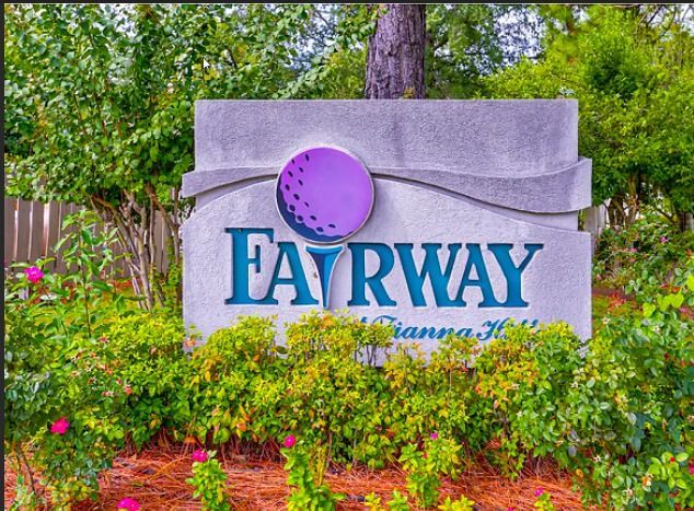 a sign for fairway is surrounded by bushes and trees