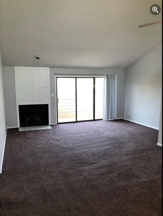 an empty living room with a fireplace and sliding glass doors .