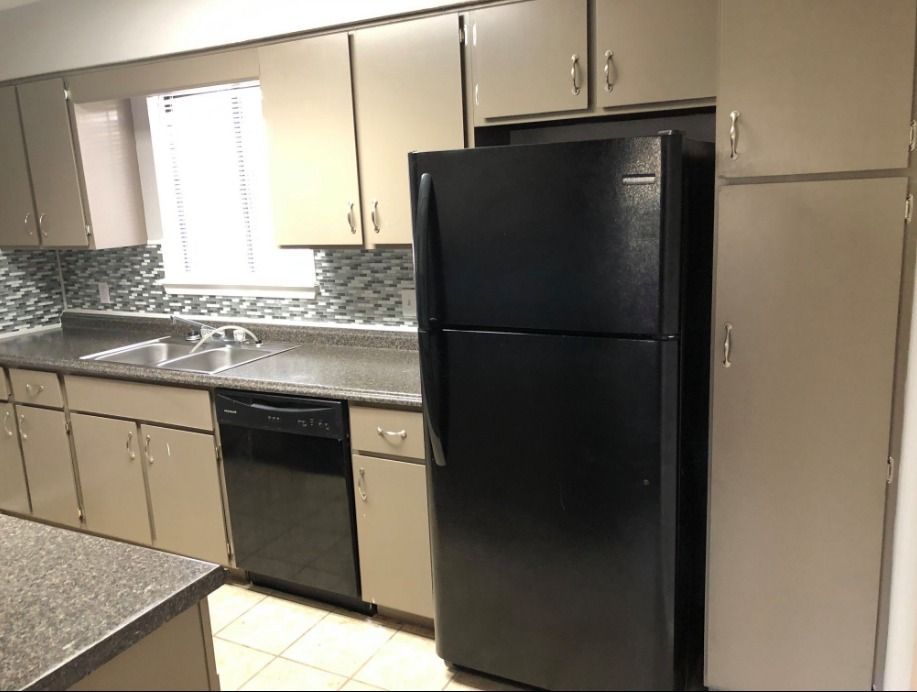 a kitchen with a black refrigerator and a sink