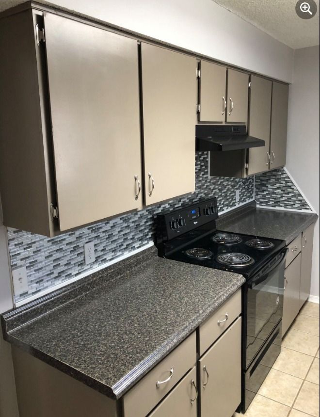 a kitchen with a stove top oven and granite counter tops