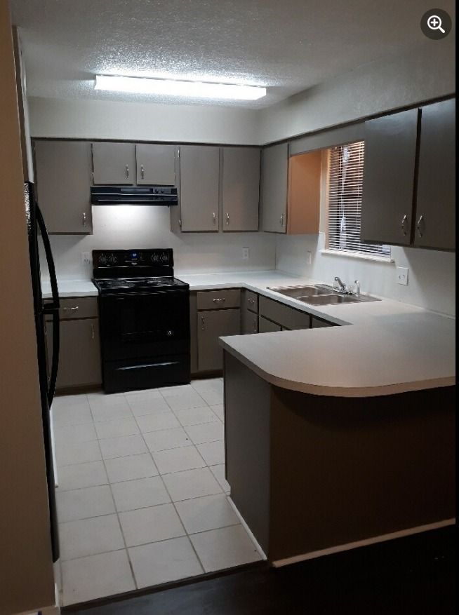 a kitchen with a stove , refrigerator , sink and cabinets