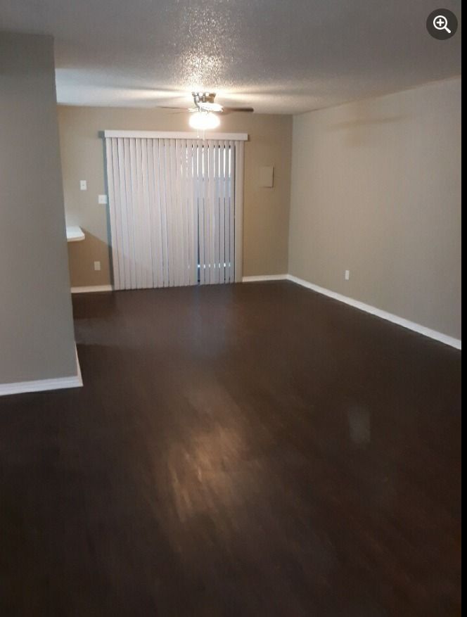 an empty living room with a sliding glass door and a ceiling fan .