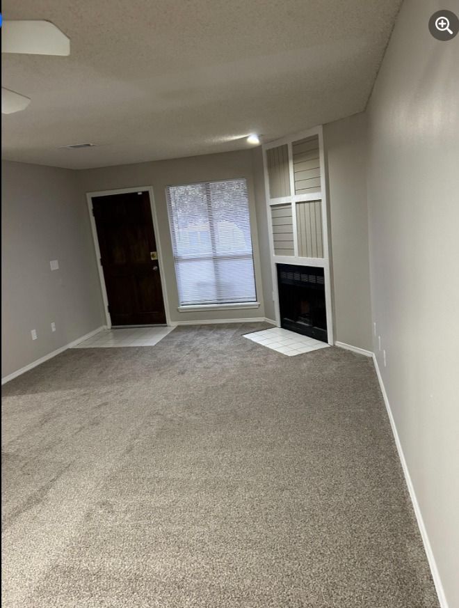 an empty living room with a fireplace and a door .