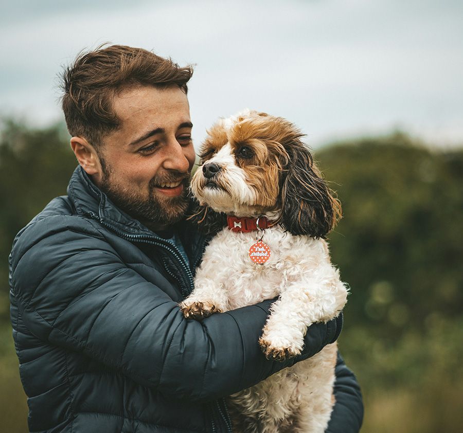 Man holding white and brown dog outside