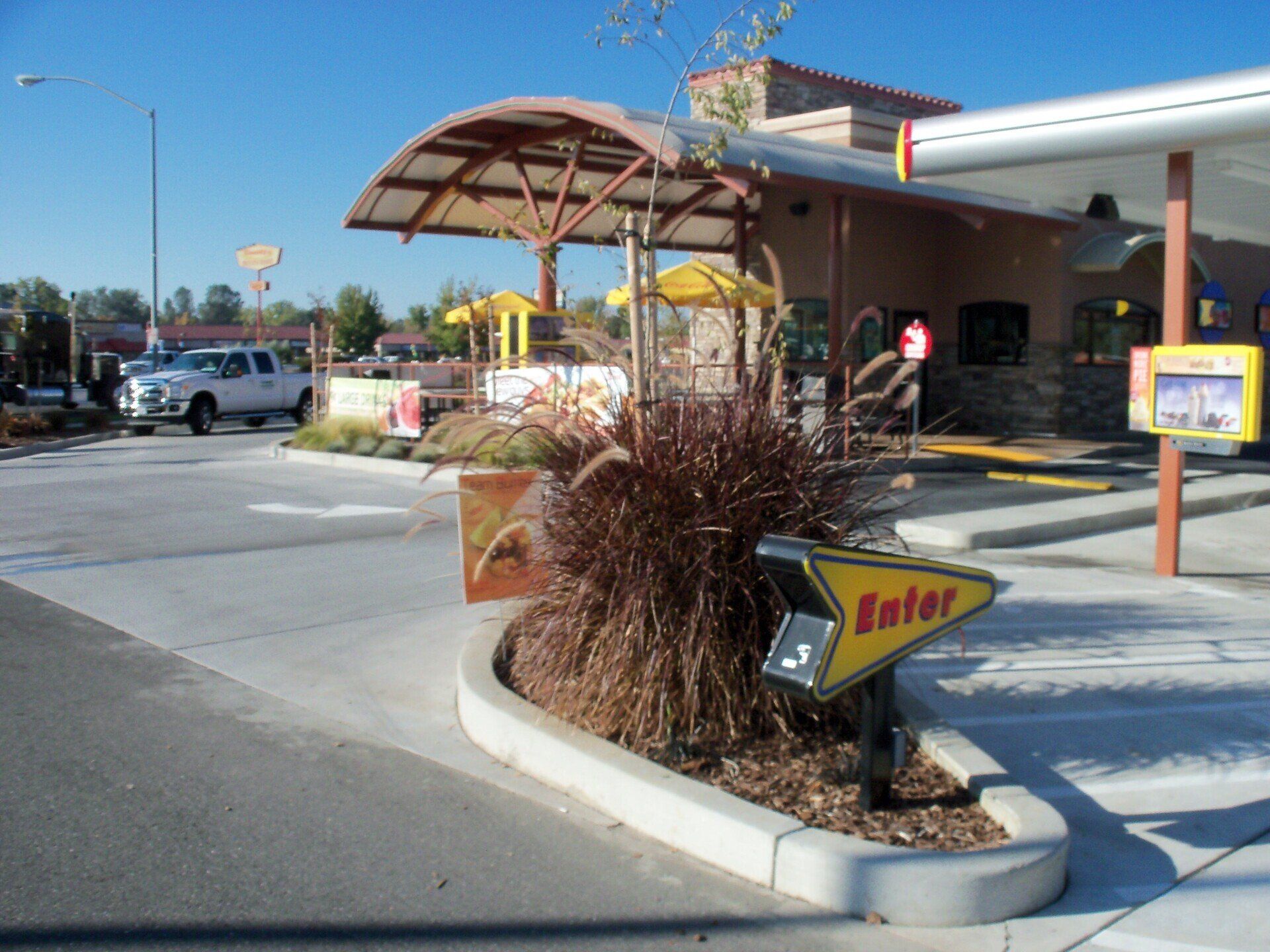 Drive-thru entrance at a restaurant with an arrow pointing to lane 3. A white truck is waiting in line.
