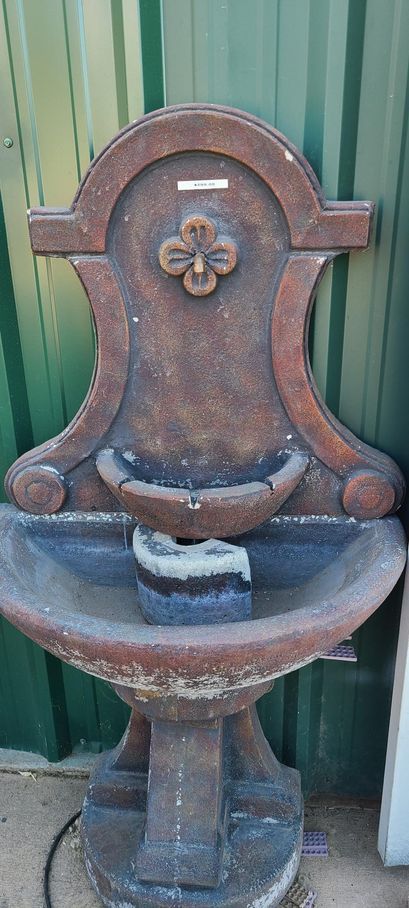 Stone wall fountain with basin and decorative elements.