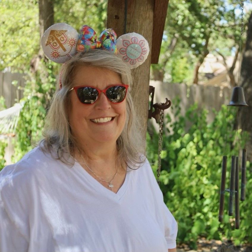photo of owner Shannon Stone smiling with sunglasses wearing Mickey ears