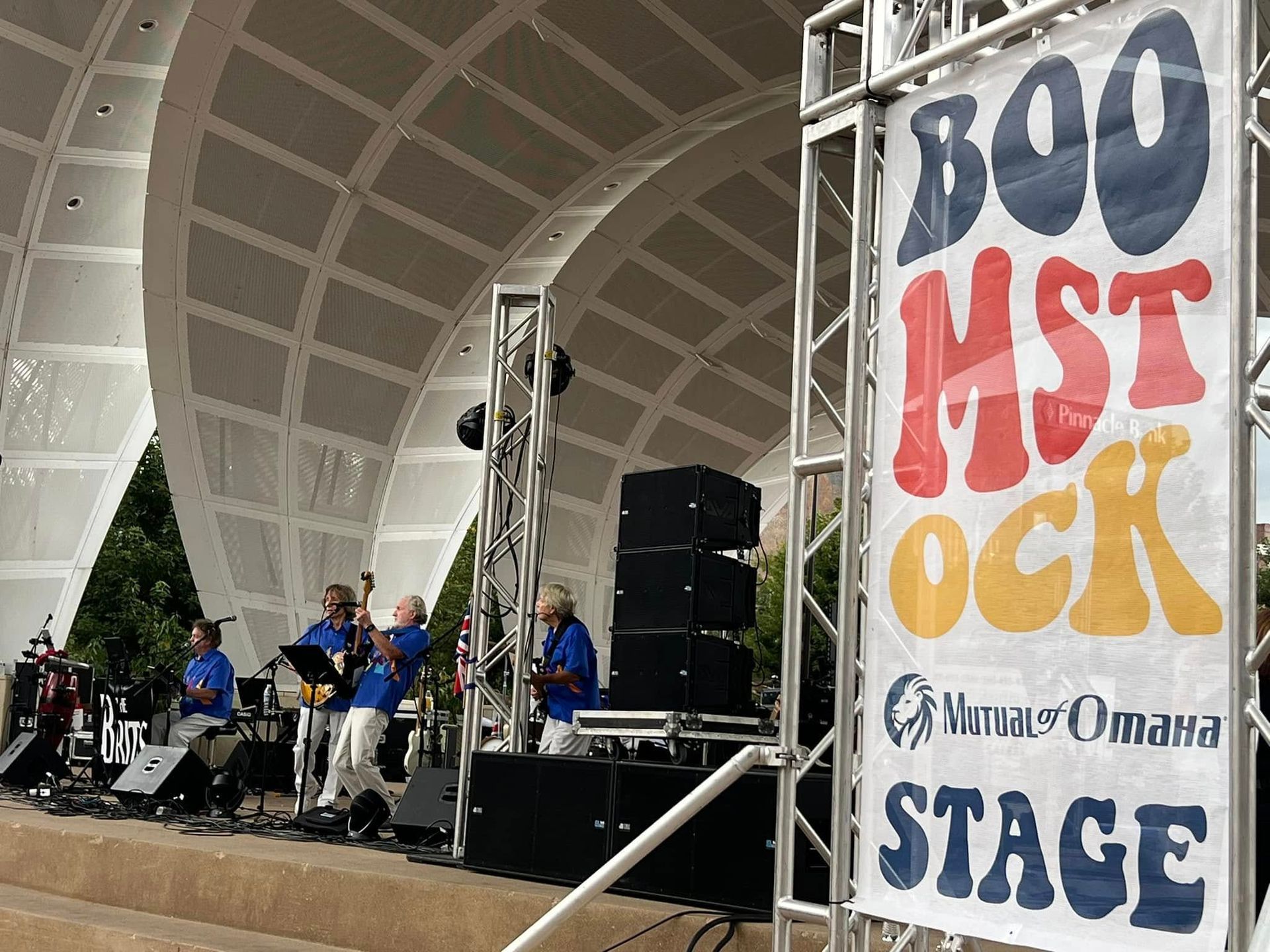 A band is playing in front of a sign that says boomstock stage