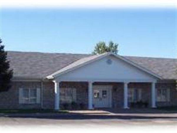 A brick building with a white porch and a gray roof.