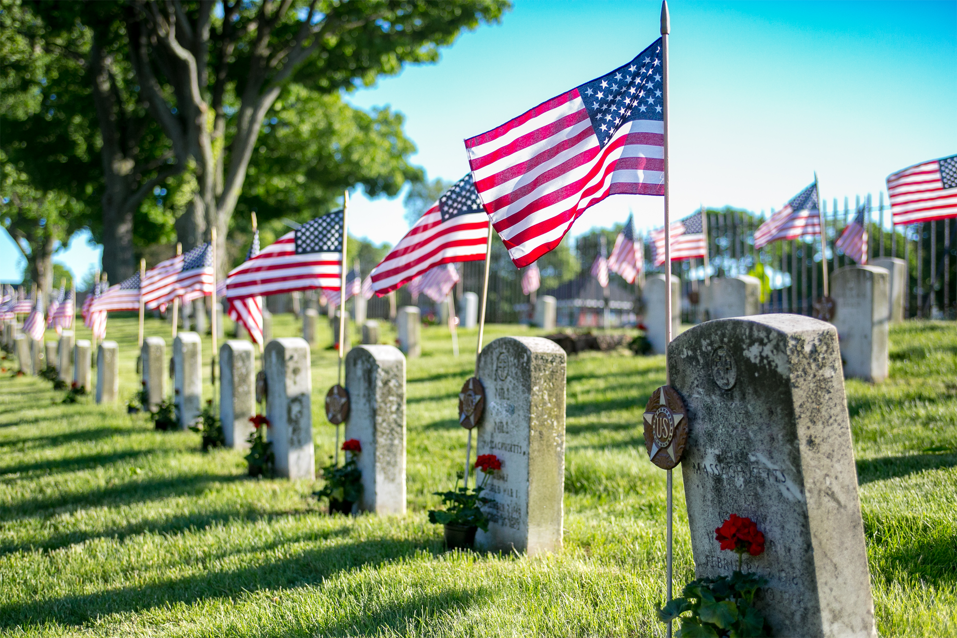 A cemetery filled with graves and american flags.