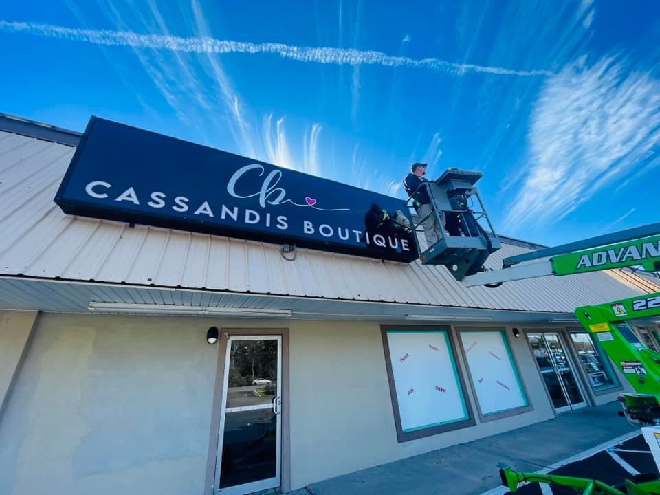 Sign installer in a lift, putting up a black sign 
