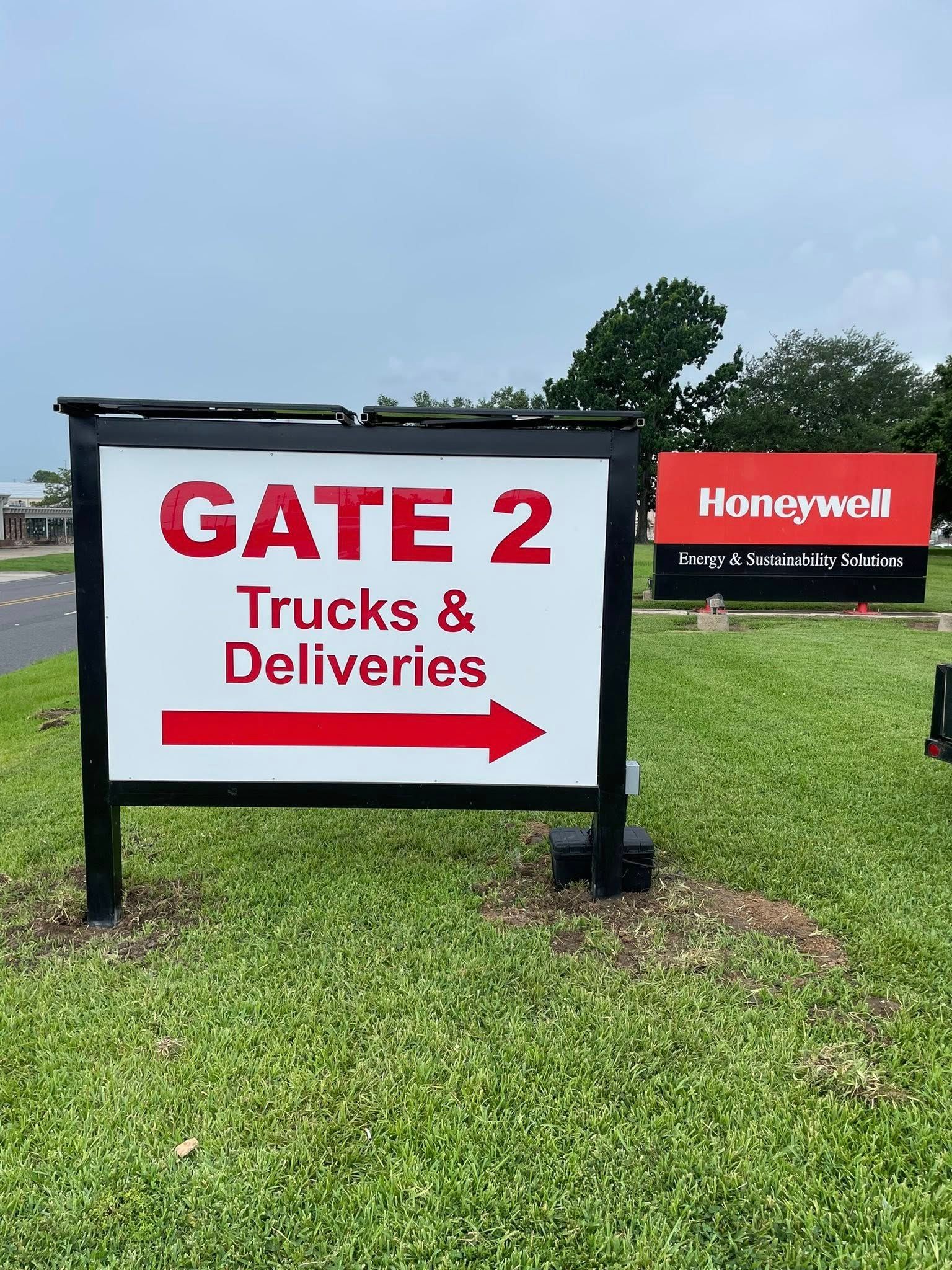 Sign for Gate 2, Trucks & Deliveries. Arrow points right.  Honeywell sign in background.