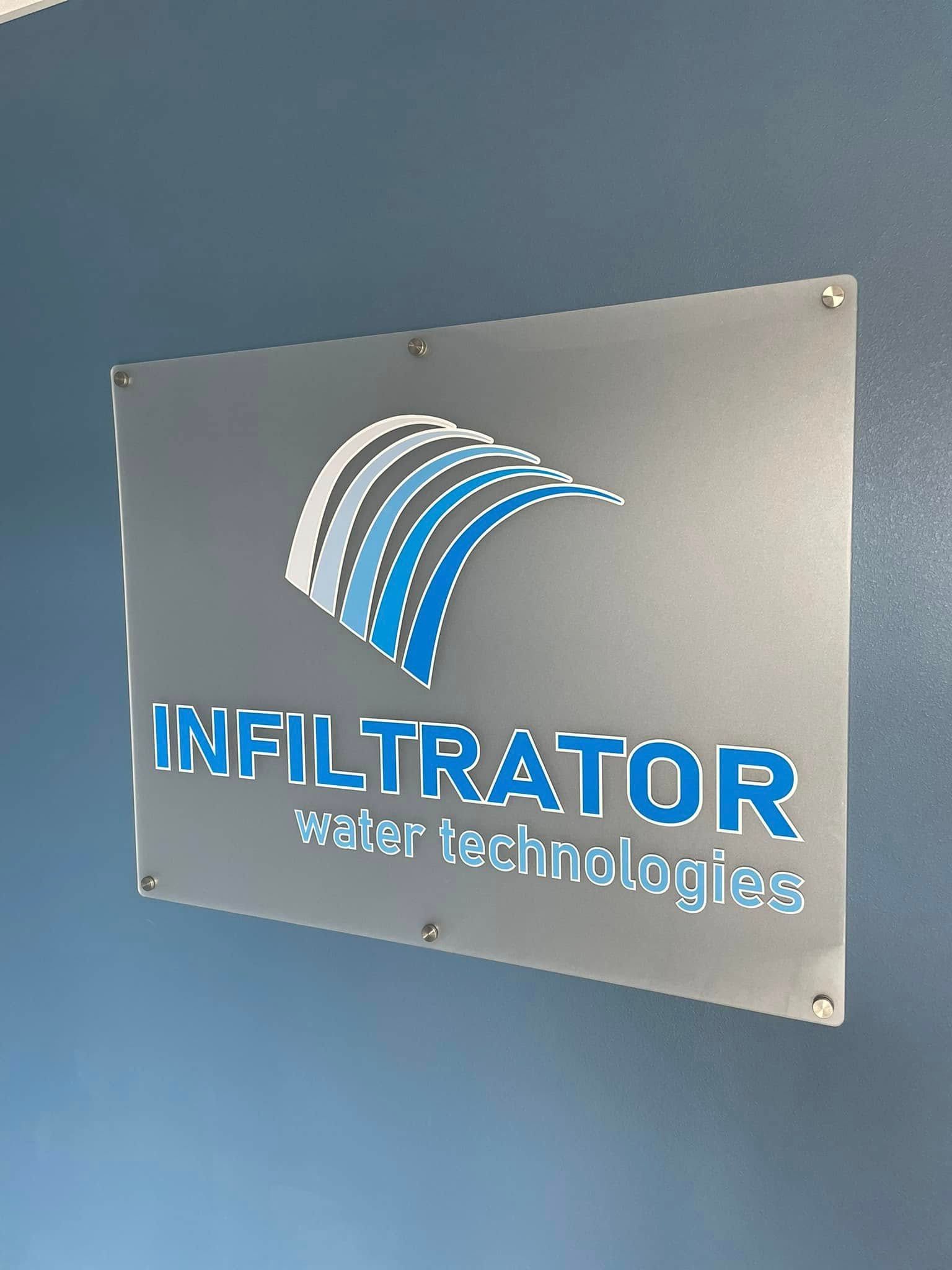 Sign for Infiltrator Water Technologies on a blue wall, silver background with blue logo and text.