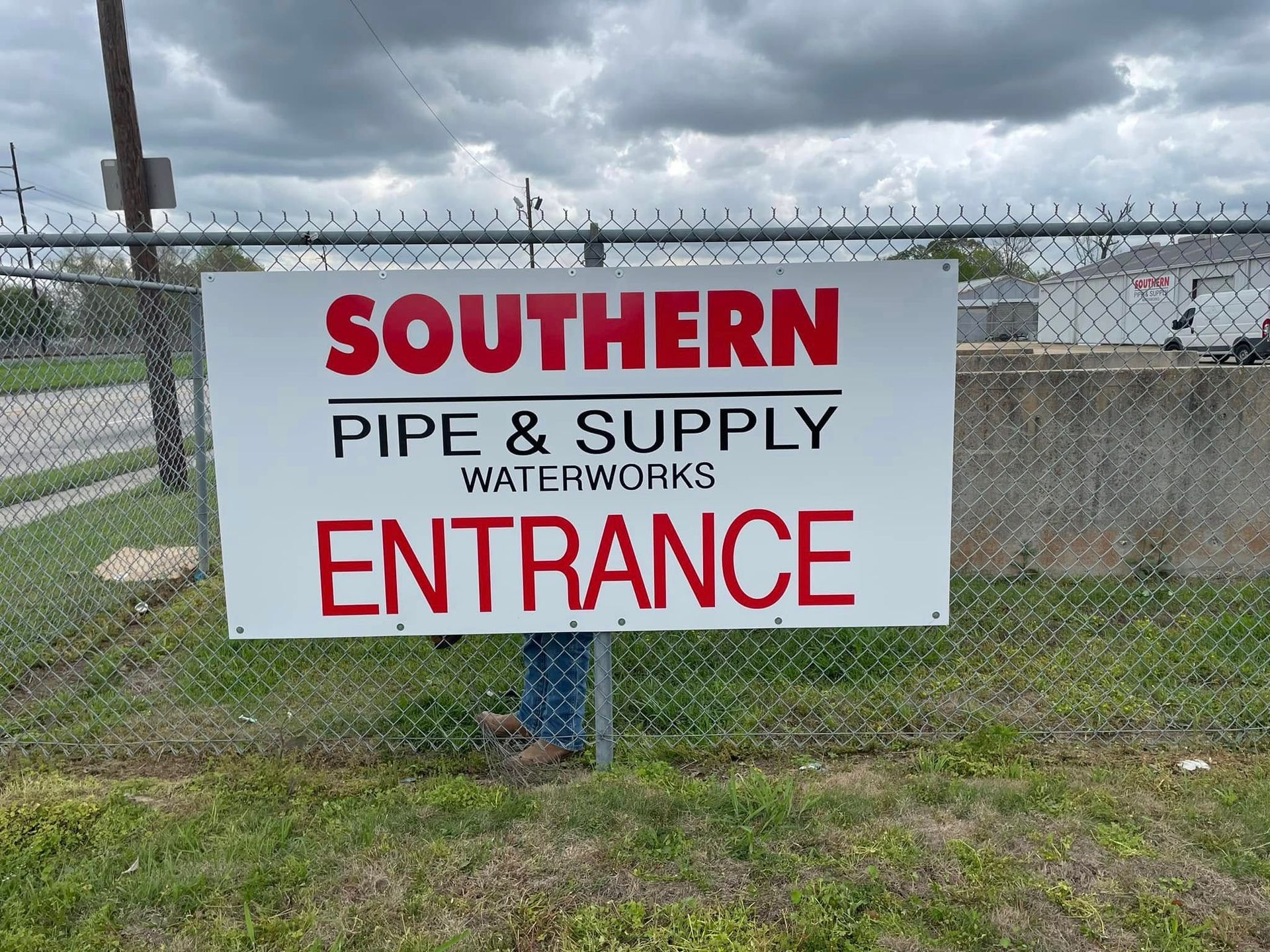 Sign for Southern Pipe & Supply Waterworks, entrance marked on a chain link fence, red and black text on a white background.