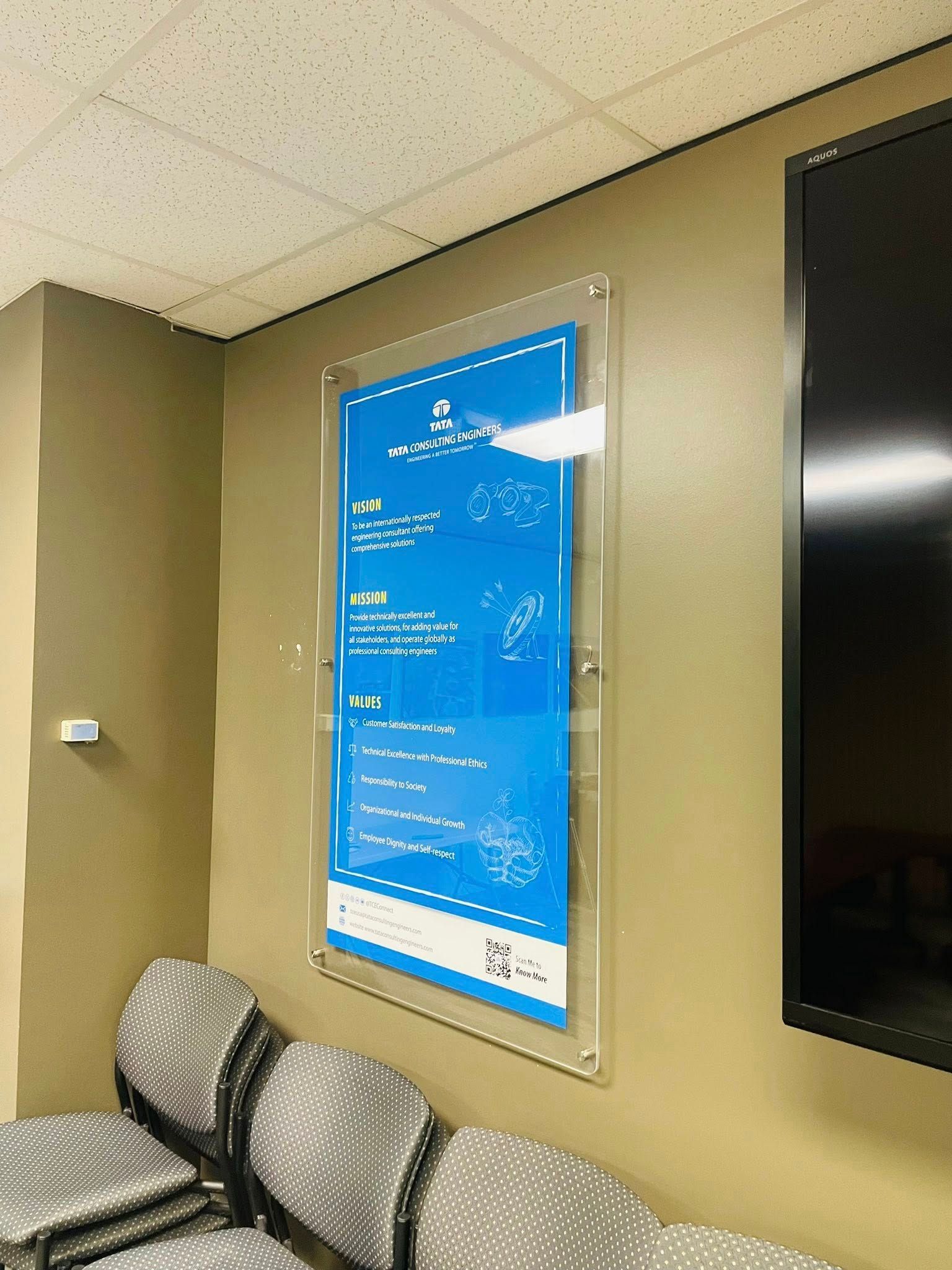 A blue poster with white text is on a beige wall, encased in clear plastic.