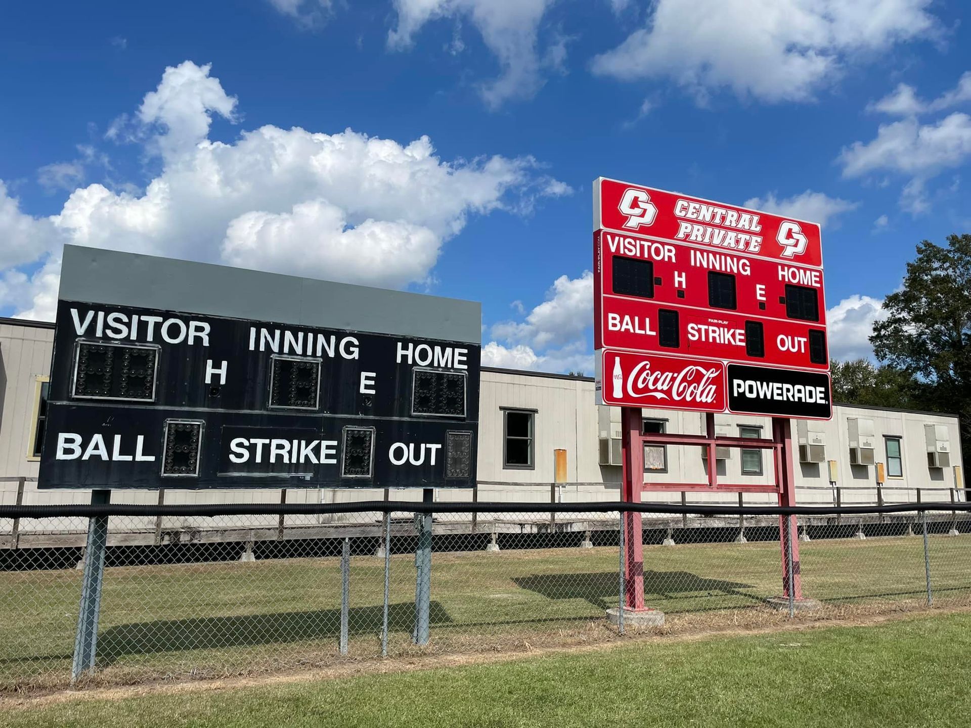 Yellow school crossing sign with silhouettes of two people walking, greenery in the background.
