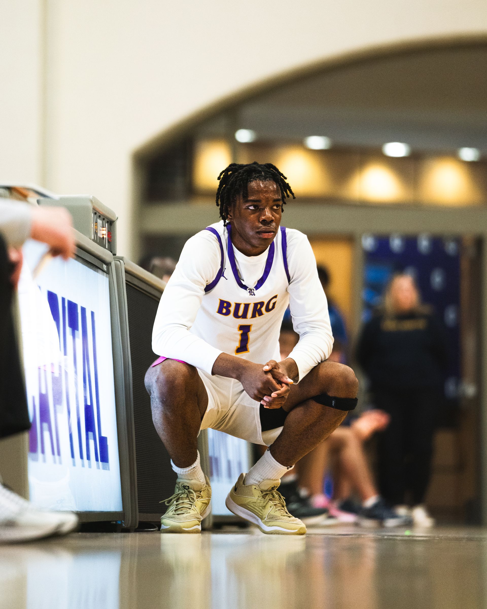 A basketball player is squatting down on the court.