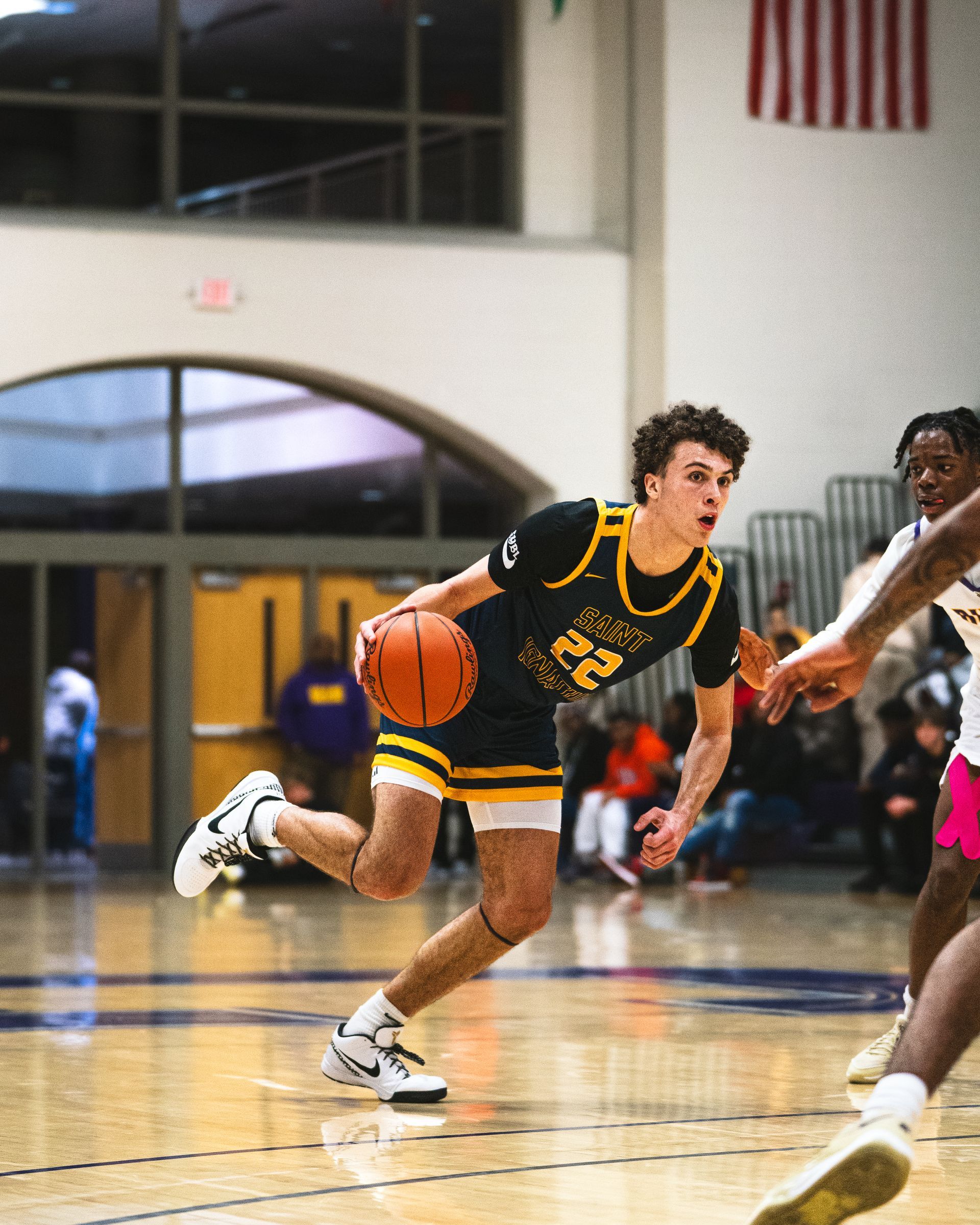 A young man is dribbling a basketball on a basketball court.