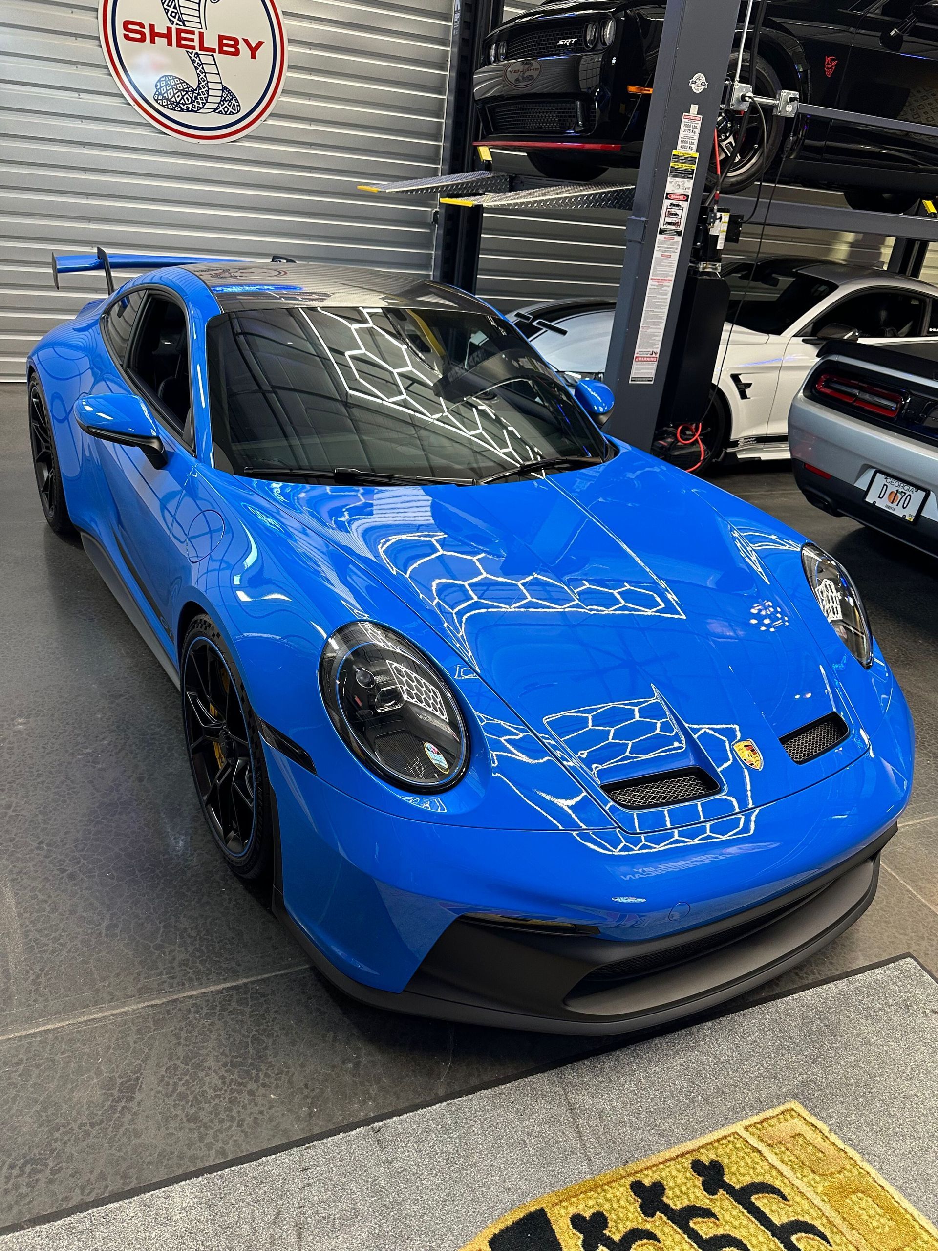 Blue Porsche 911 GT3 parked in a garage with a Shelby sign.