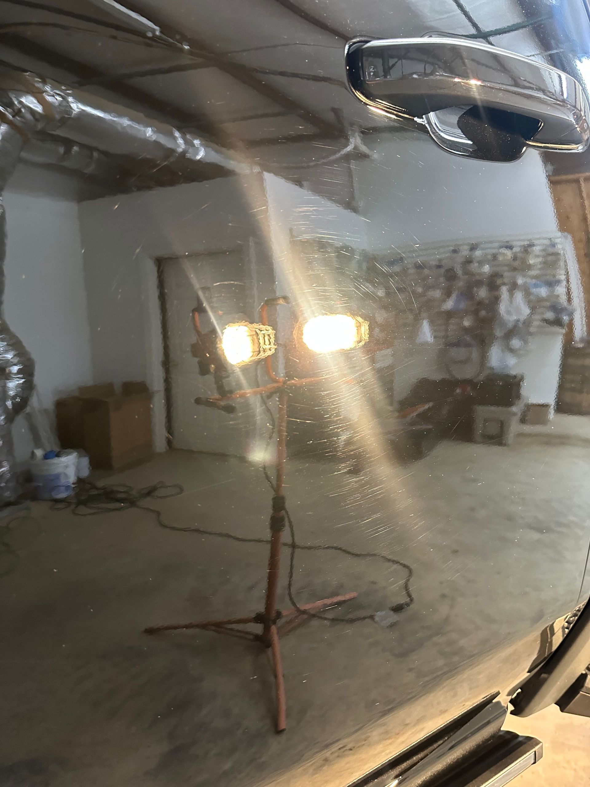 A light fixture in a workshop, reflecting on a vehicle's surface.