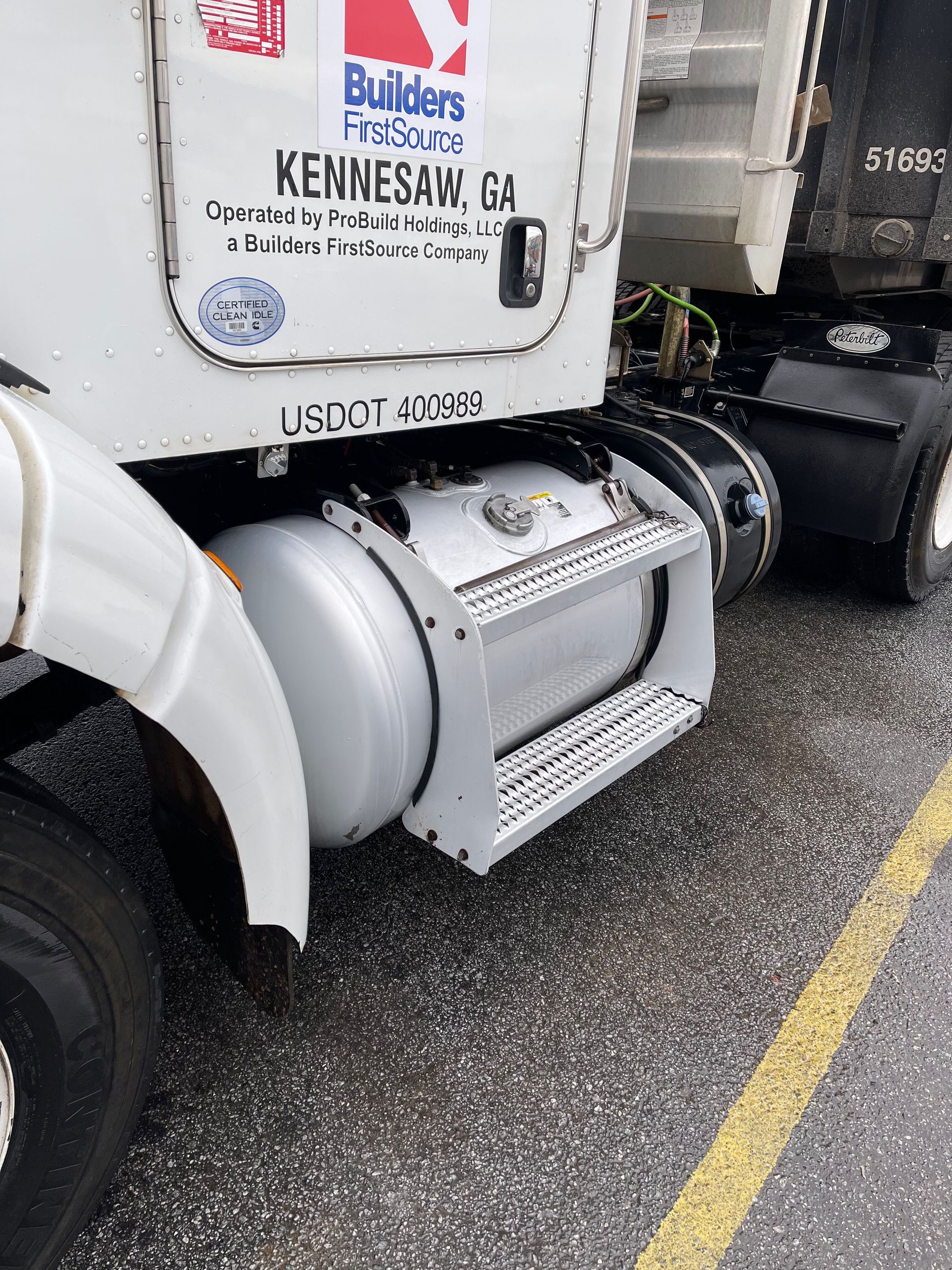 Side of white semi-truck with a fuel tank and steps. 
