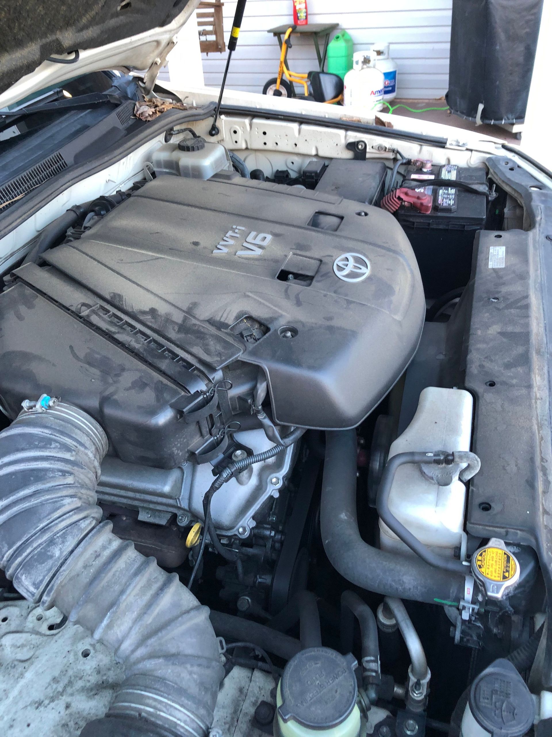 White car engine compartment with a plastic cover over the engine.