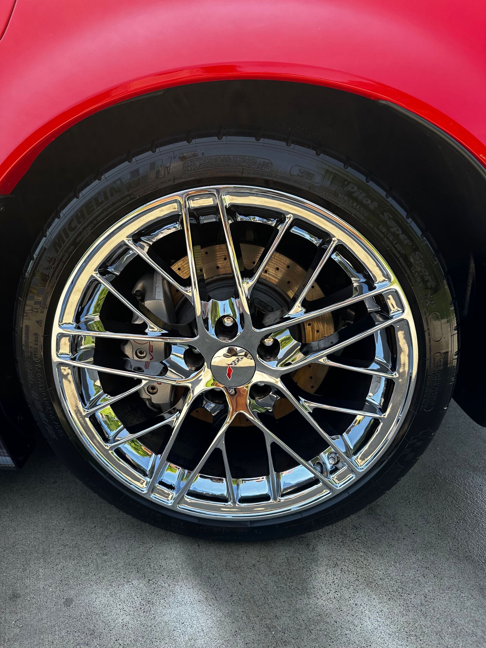 Chrome car wheel on a red car with black tire; angled view.