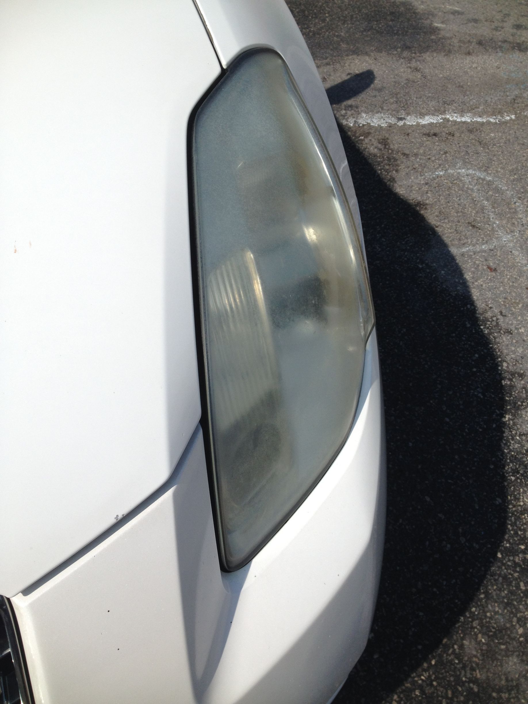 Cloudy headlight on a white car.