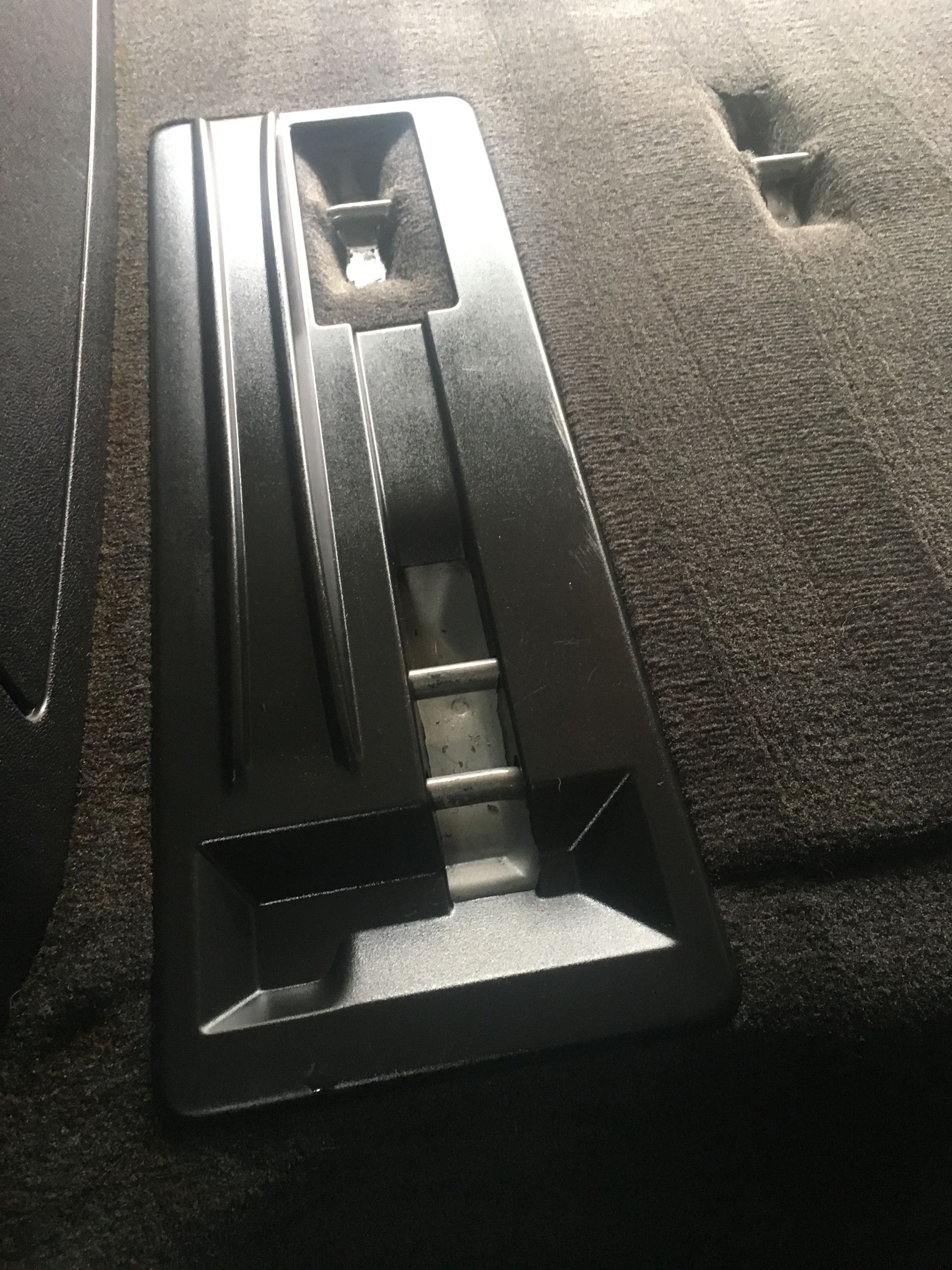 Black plastic car seat latch on a dark carpeted surface.