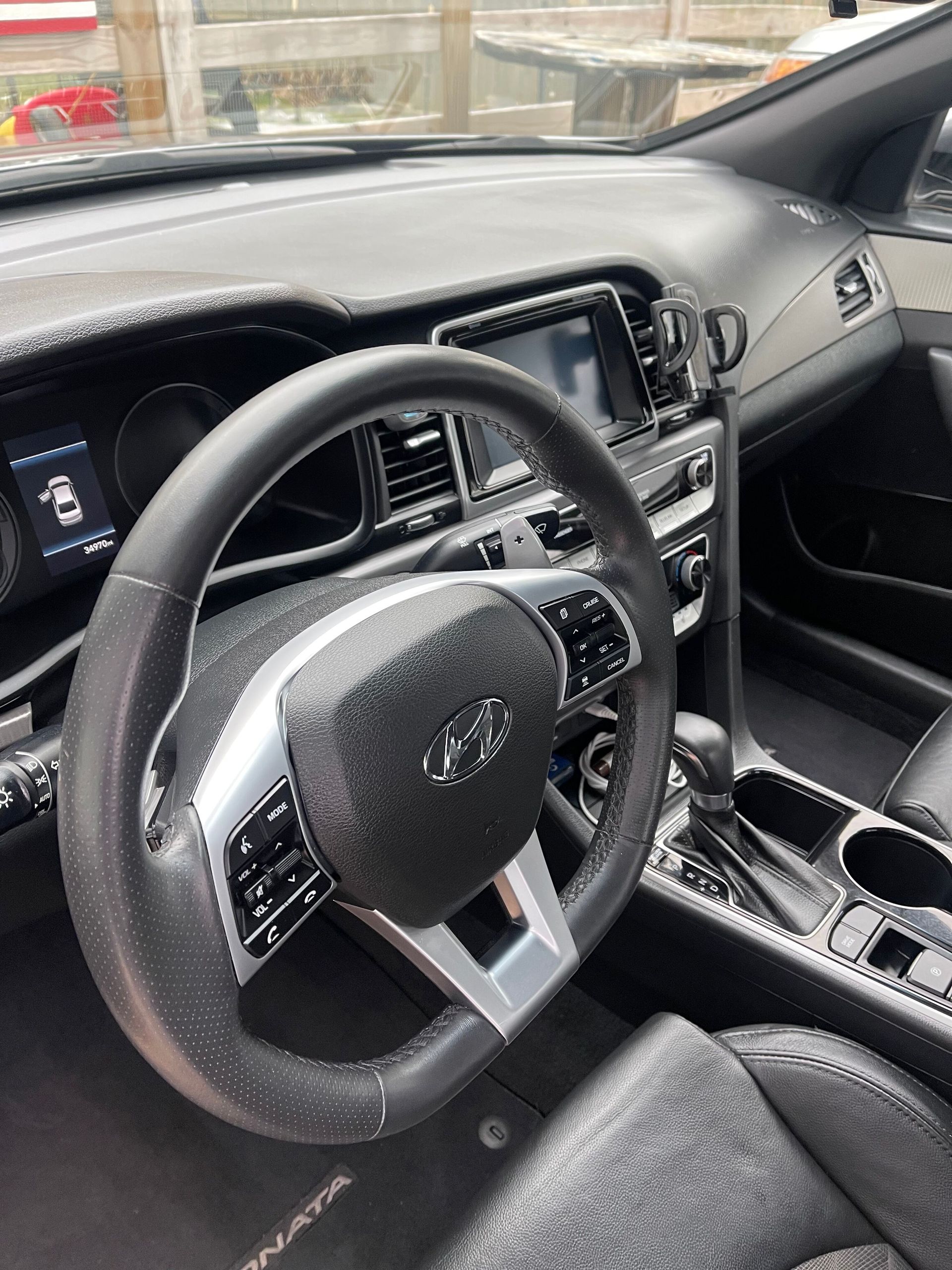 Interior of a Hyundai Sonata, steering wheel in focus, black dashboard, infotainment screen.