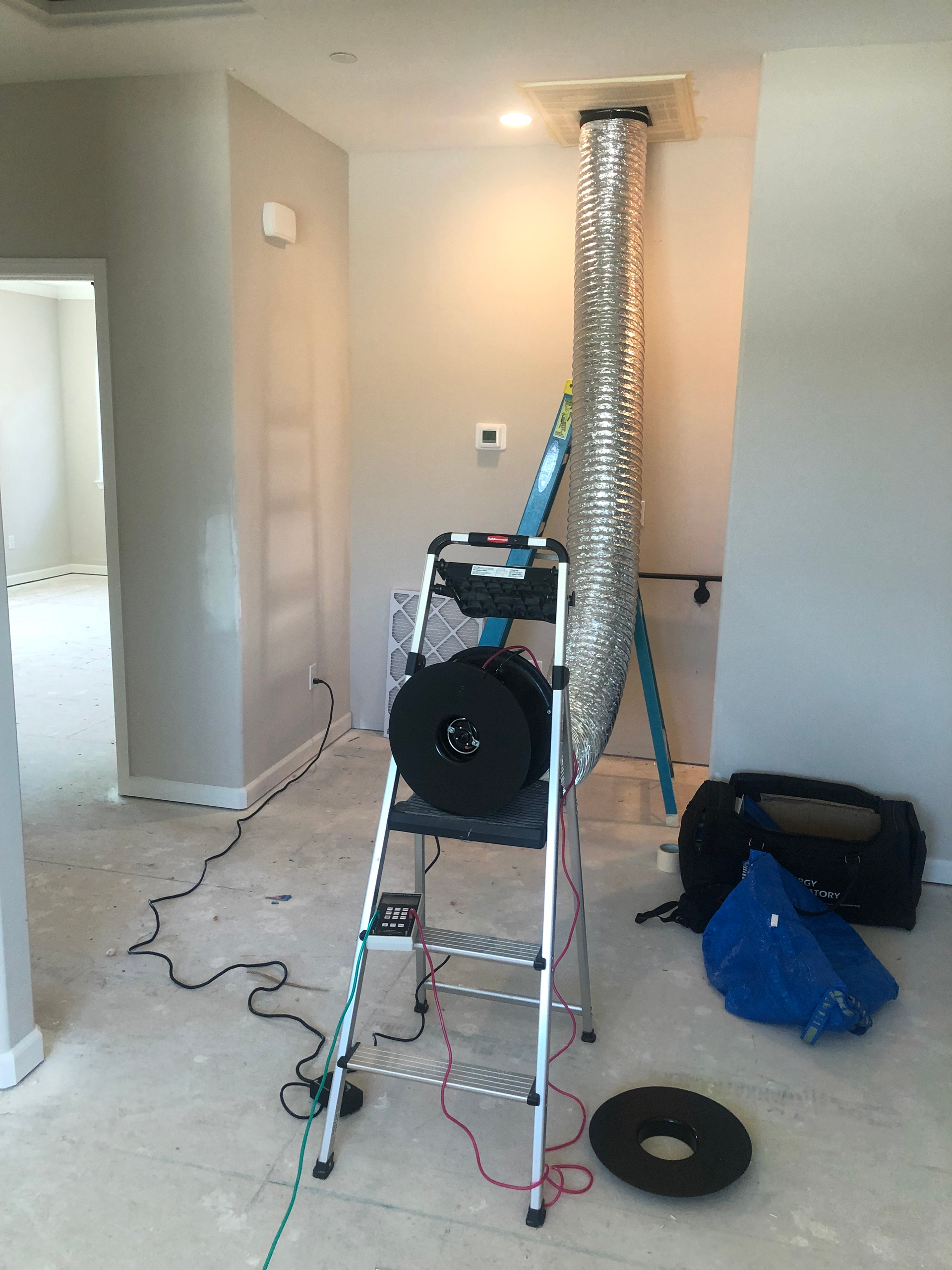 A ladder is sitting next to a duct in a room.
