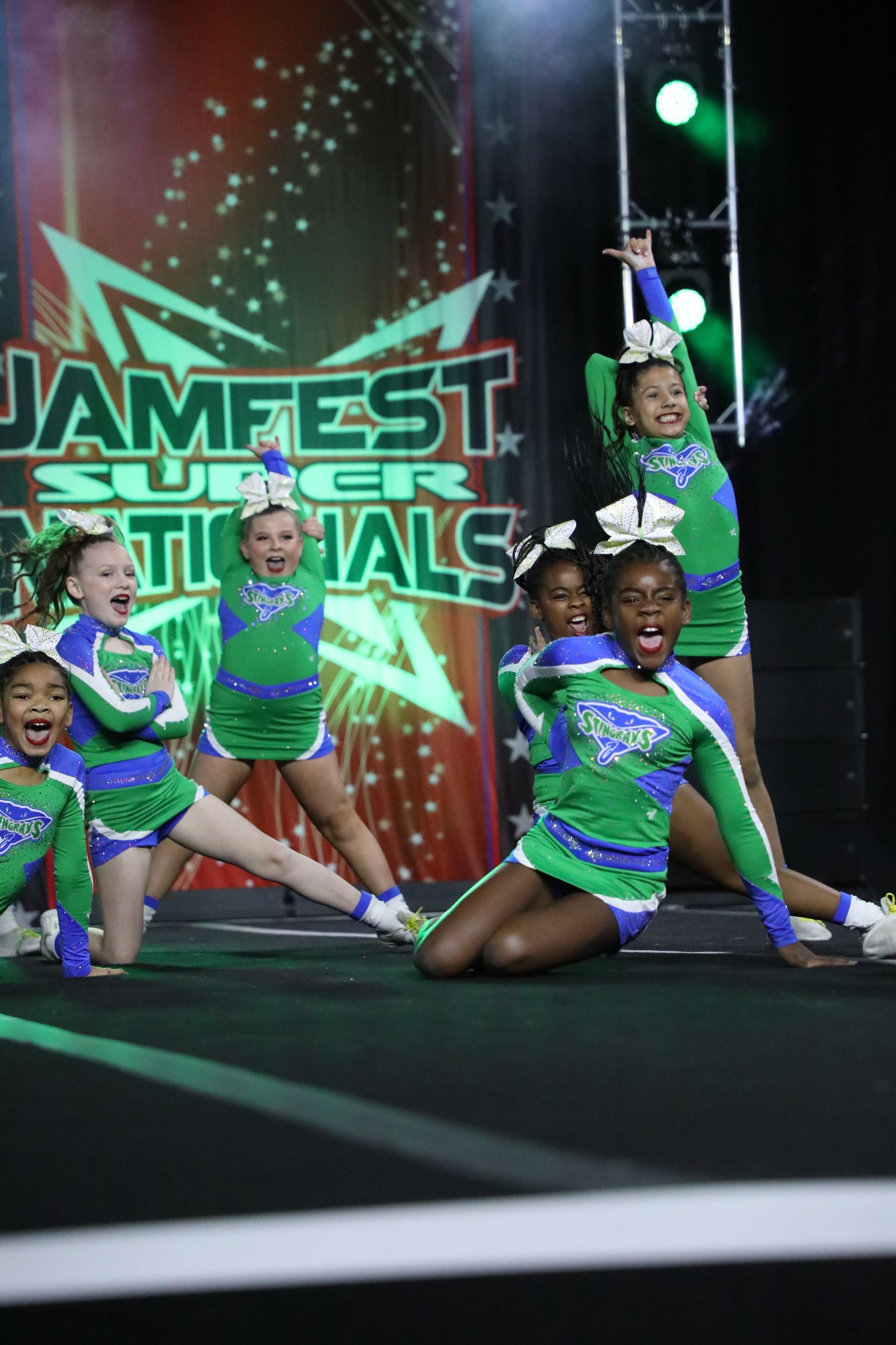 A group of cheerleaders are posing for a picture on a stage.