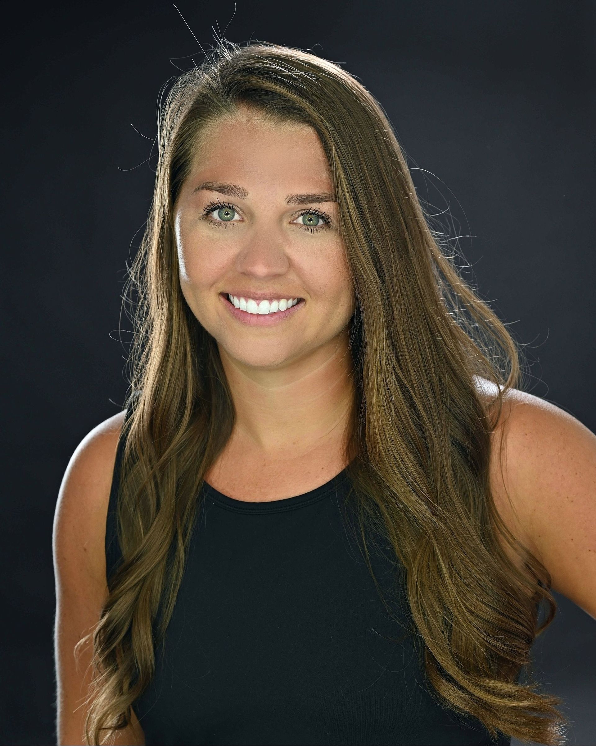 The woman is wearing a black tank top and smiling for the camera.