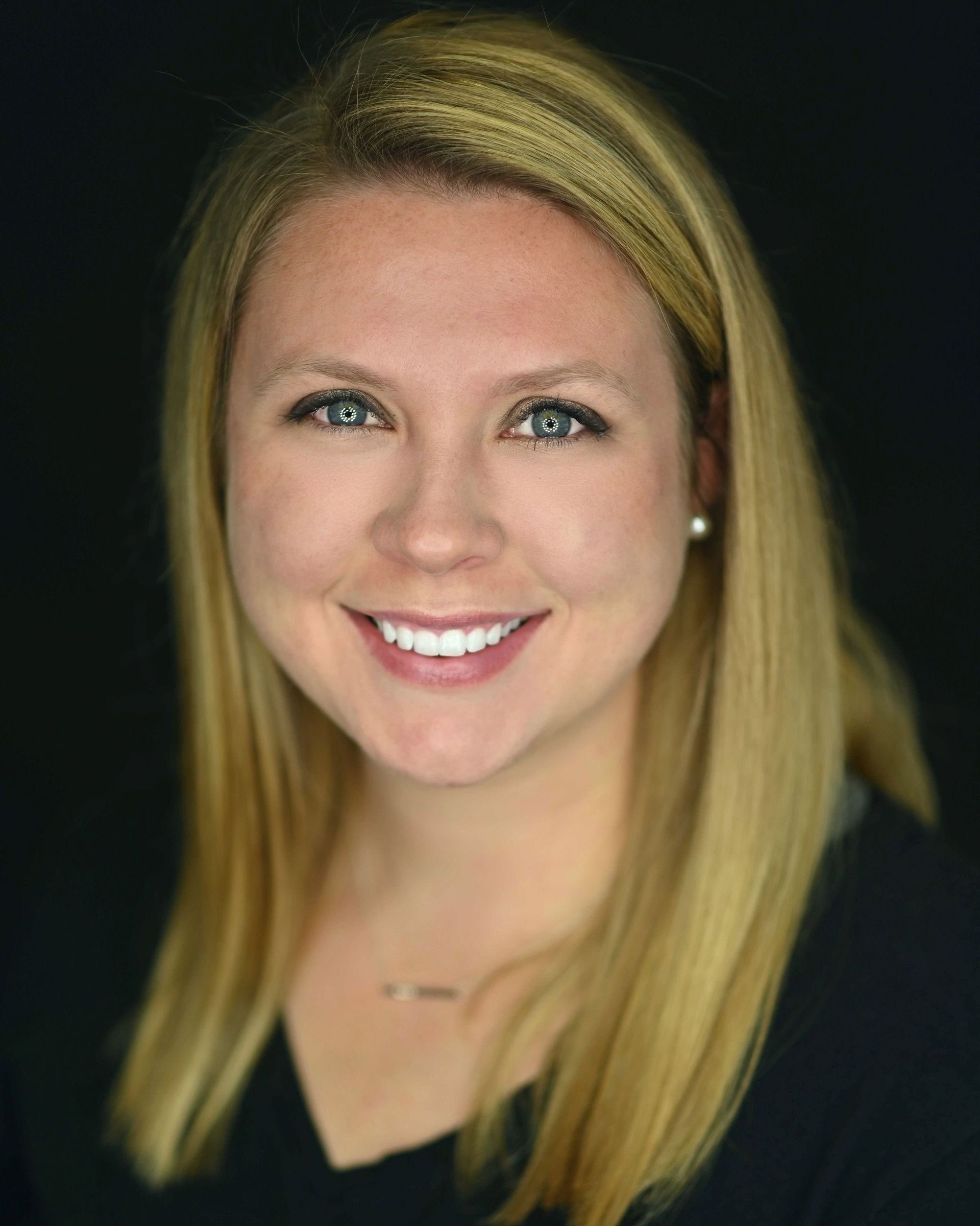 A woman with blonde hair and blue eyes is smiling for the camera.