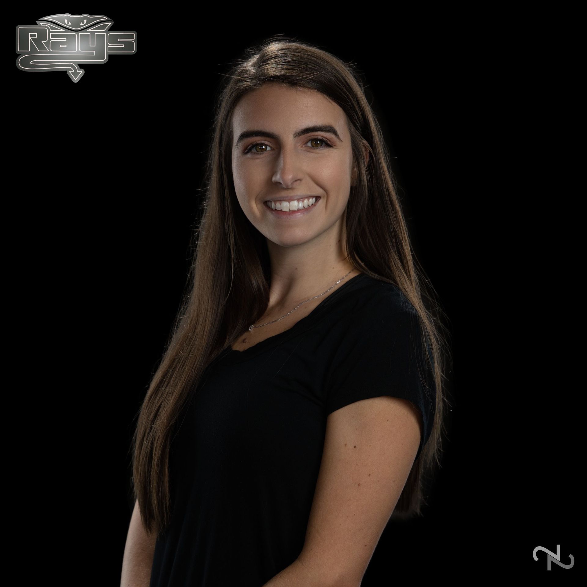 A woman in a black shirt is smiling in front of a rams logo