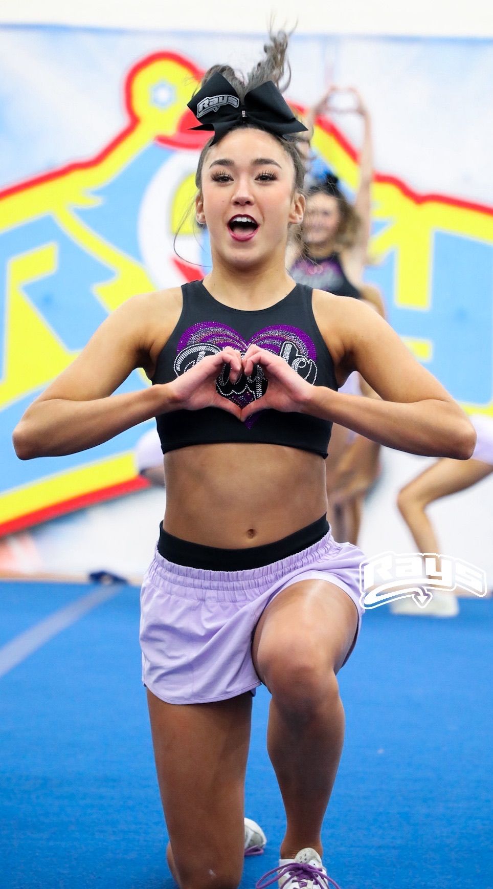 A cheerleader is making a heart shape with her hands.