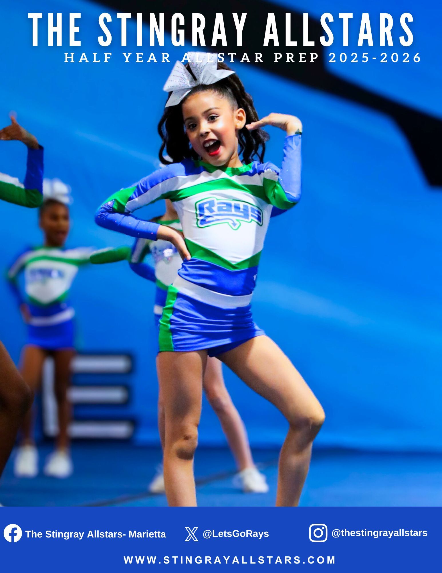A group of cheerleaders are posing for a picture in front of a large screen.