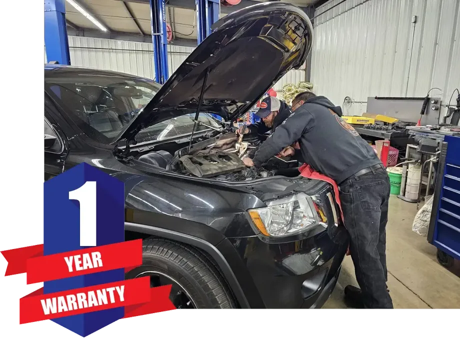 Two people are working on a black jeep in a garage | Guaranteed Auto Repair