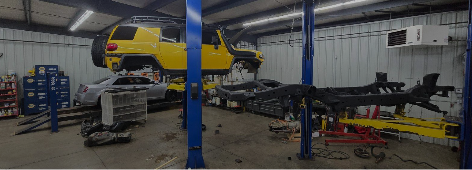 A yellow car is sitting on a lift in a garage | Guaranteed Auto Repair