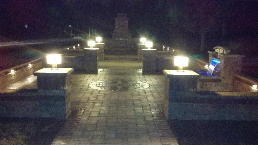 A brick walkway with lights on it at night.