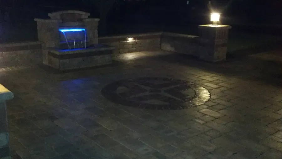 There is a waterfall in the middle of the patio at night.