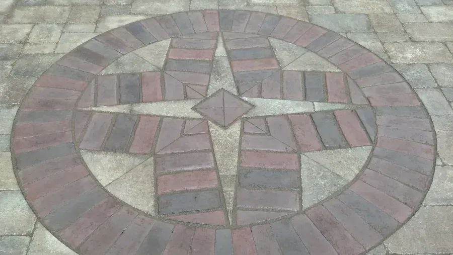 A circular design made of bricks on a patio.
