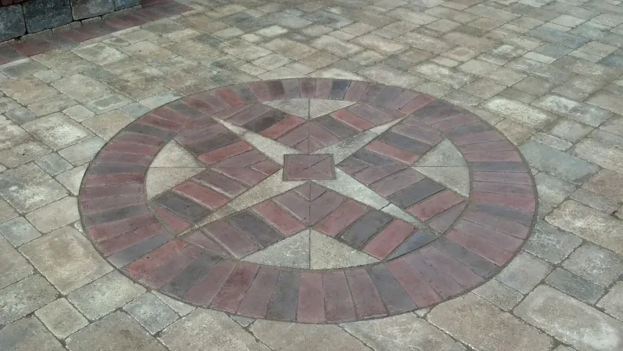 A circular pattern made of bricks on a patio.