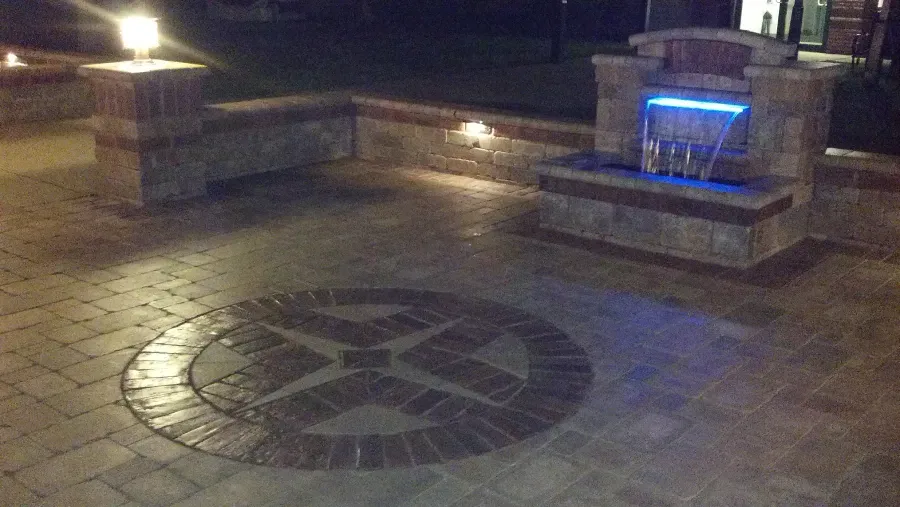 A brick patio with a fountain in the middle of it