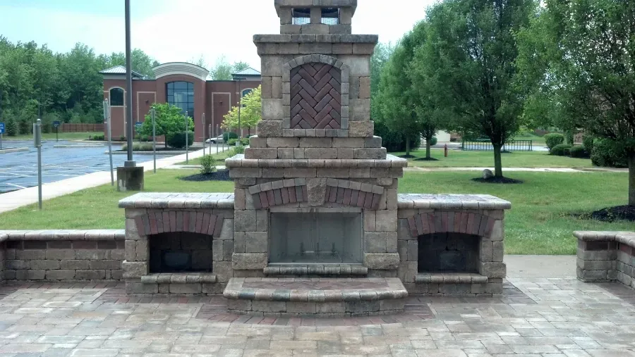A brick fireplace in a park with a building in the background