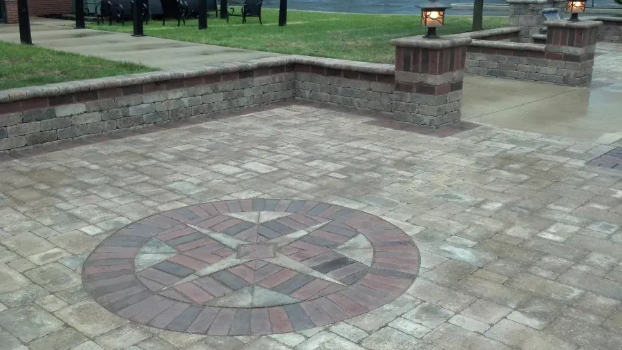 A brick patio with a circular design in the middle.